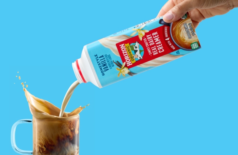 Horizon Organic coffee creamer being poured from carton into iced coffee with dramatic splash and swirl.