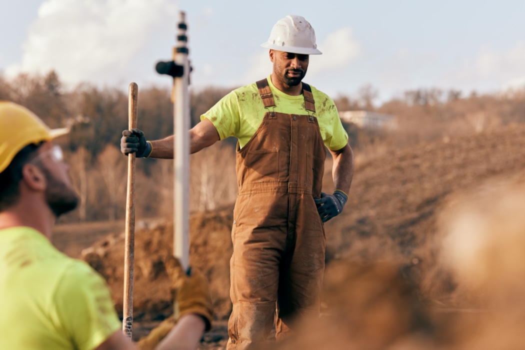 Construction worker in overalls walking on a job site wearing safety gear