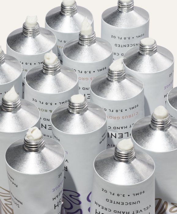Naked & Thriving skincare collection in silver aluminum tubes flat lay on white background