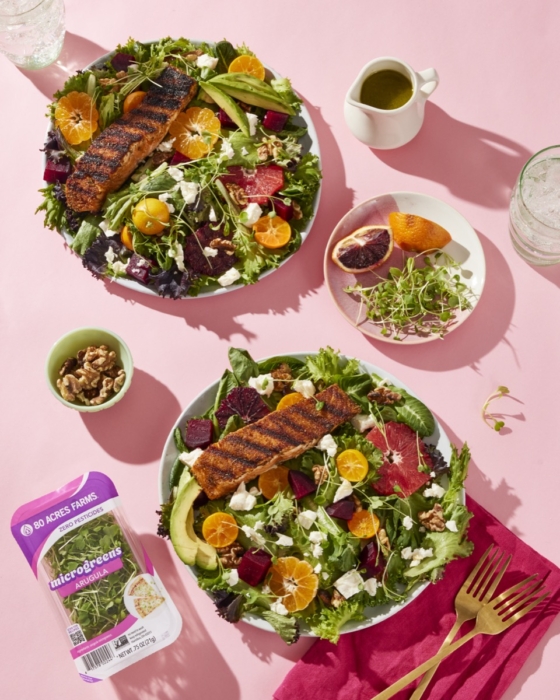 Overhead shot of 80 Acres Farms salad with grilled chicken and mixed toppings on pink background