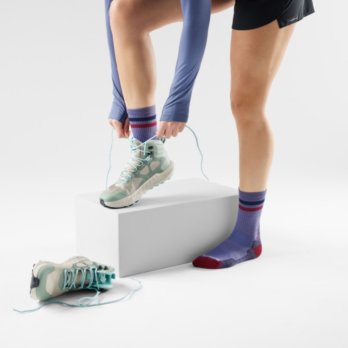 Person stepping onto a white cube wearing socks and sneakers in a studio setup