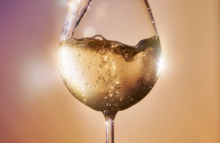 Sparkling white wine being poured into a glass with bubbles and splash captured in high-speed liquid photography