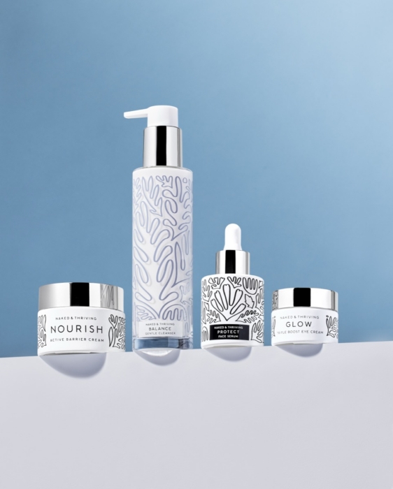 Four Naked & Thriving skincare products arranged on a blue gradient surface: Nourish Active Barrier Cream jar, Balance Gentle Cleanser pump bottle, Protect Face Serum dropper, and Glow Triple Boost Eye Cream jar, all featuring white and silver packaging with organic botanical line art