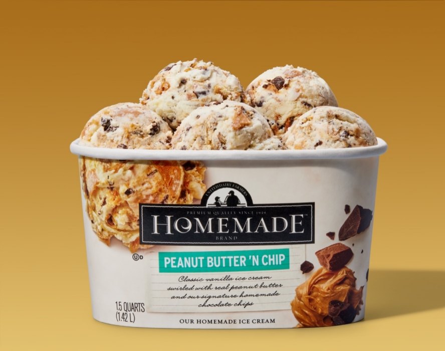 Homemade Brand Peanut Butter 'N Chip ice cream 1.5 quart container open and overflowing with multiple generous scoops of vanilla ice cream with peanut butter swirls and chocolate chips, on a warm golden background