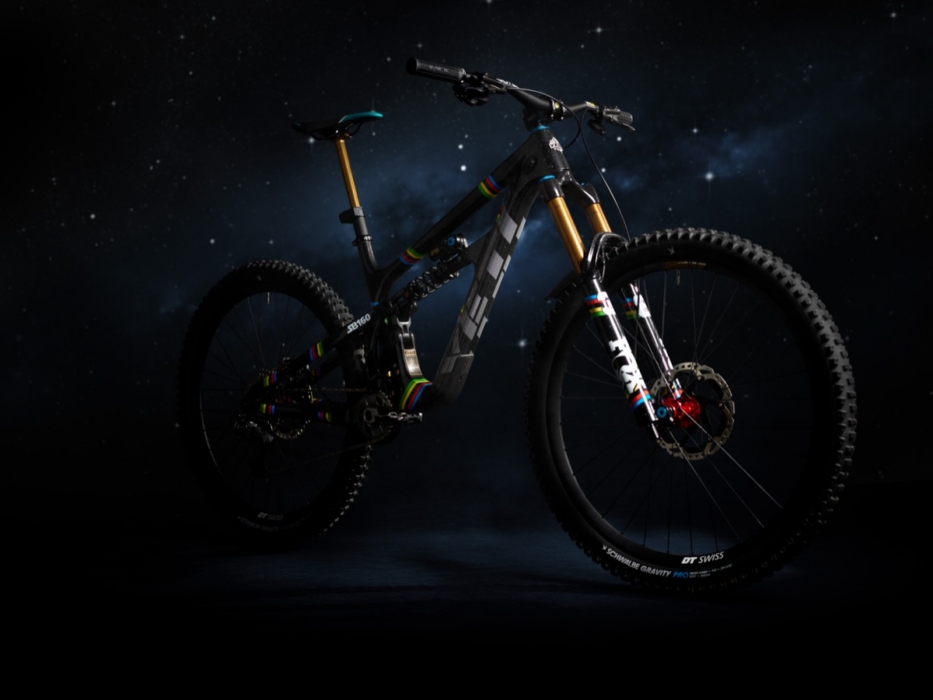 Full-length three-quarter rear studio portrait of Yeti SB160 Richie Rude 2025 EDR World Champion Special Projects mountain bike against cosmic starfield background, showing Fox 40 Factory fork, DT Swiss Schwalbe Gravity Pro wheelset, and UCI rainbow stripe accents throughout