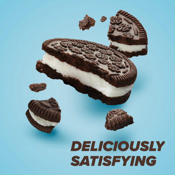 Pure Protein Cookies and Cream protein bar with chocolate coating and cream-filled cookie pieces on dark background