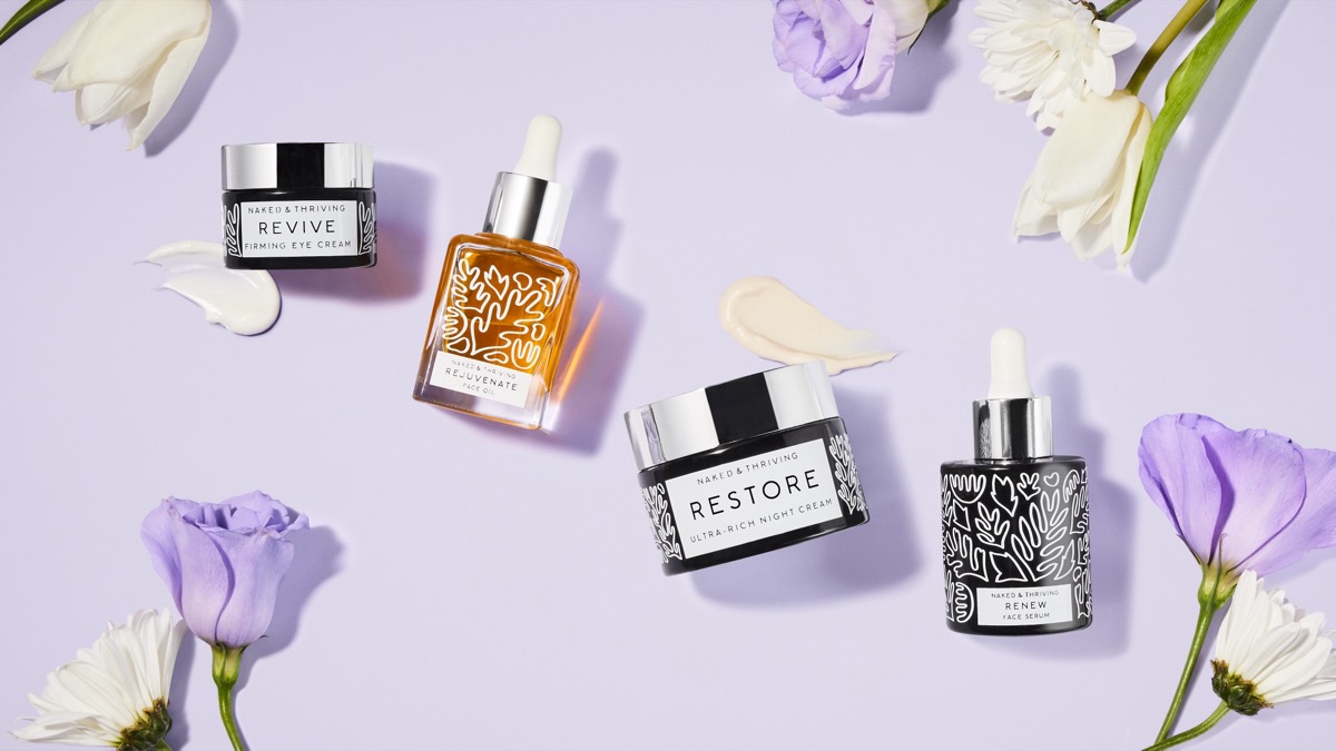 Naked & Thriving Restore facial oil and skincare bottles flat lay on soft lavender background