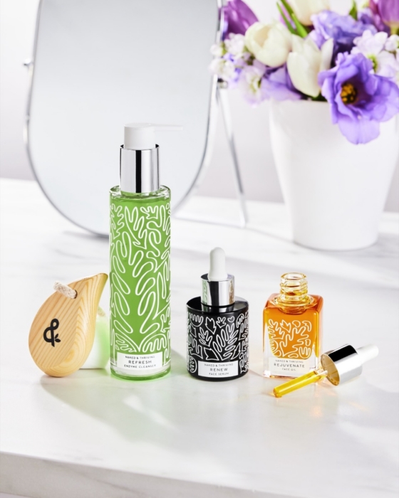 Naked & Thriving green botanical skincare collection with purple flowers on white background