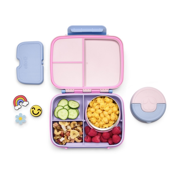 Ello bento lunch box filled with mac and cheese, raspberries, trail mix, and cucumber slices with rainbow and smiley charms on white background