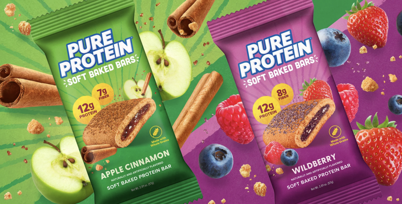 Two Pure Protein Soft Baked Bar packages in Apple Cinnamon and Wildberry flavors surrounded by fresh apples, cinnamon sticks, berries, and a cross-section of each bar