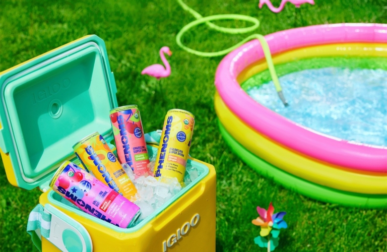 Yellow Igloo cooler packed with ice and colorful assorted freezer pops next to an inflatable rainbow kiddie pool with flamingo yard décor