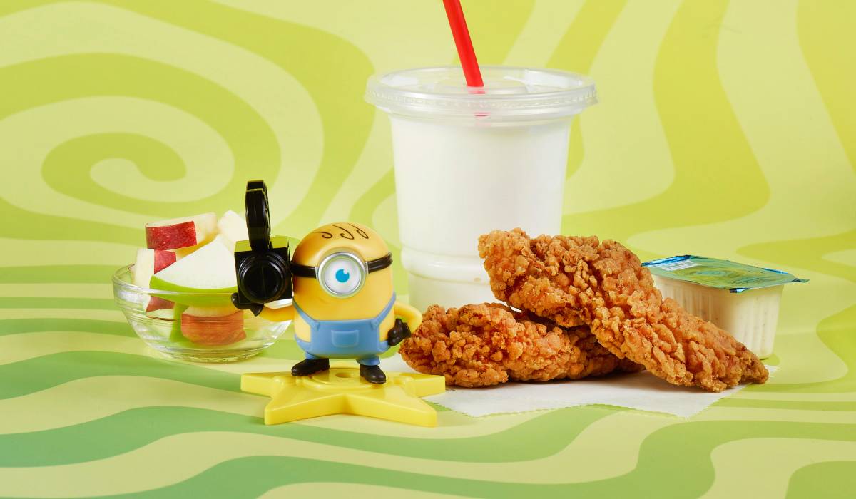 Wendy's kids meal featuring chicken tenders, apple slices, milk, and a Minions collectible toy on a green swirl background