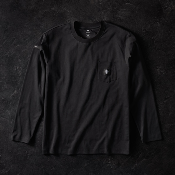 Black long sleeve pocket t-shirt with embroidered compass logo on chest pocket and sleeve tag, laid flat on dark stone background