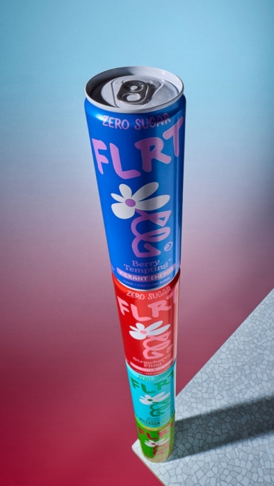 Stack of three FLRT zero sugar energy drink cans in blue, red, and teal balanced vertically against a pink and blue gradient background