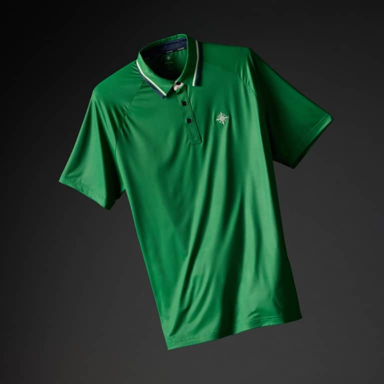 Kelly green golf polo shirt with navy and white striped collar and embroidered compass logo on a dark background
