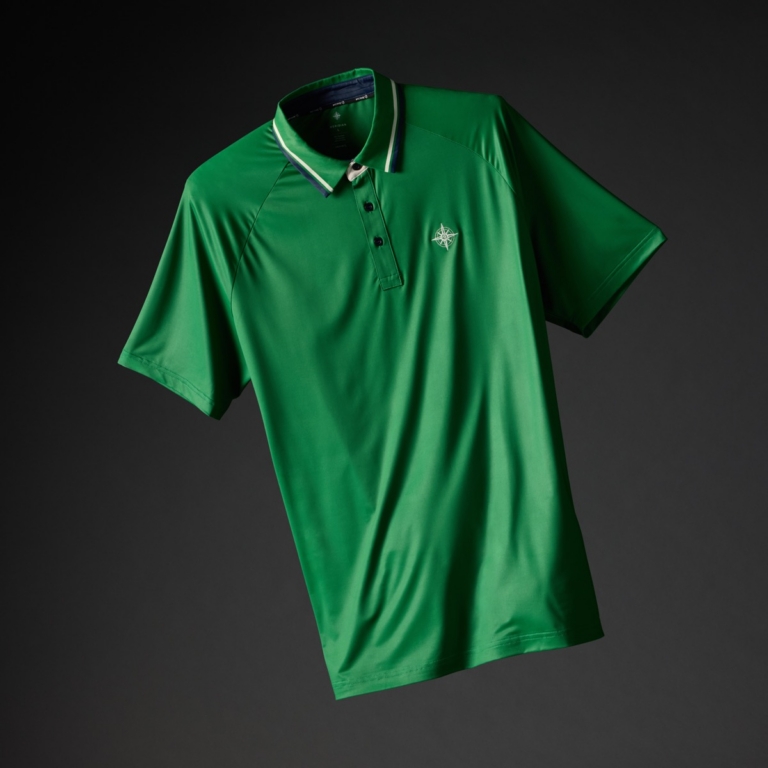 Kelly green golf polo shirt with navy and white striped collar and embroidered compass logo on a dark background