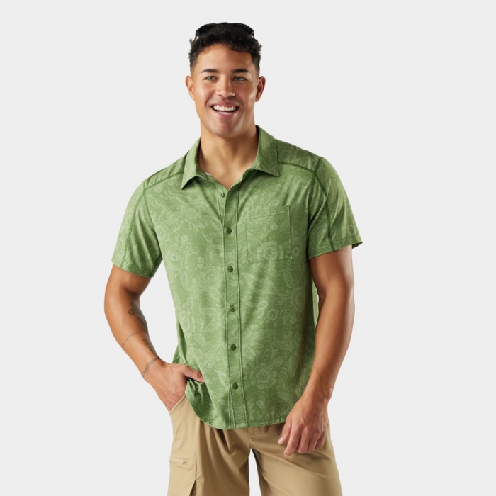 Male model wearing a green short-sleeve outdoor shirt and tan shorts photographed on white.