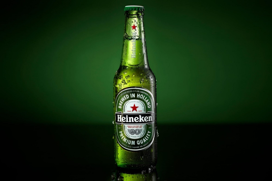 Cold Heineken beer bottle photographed against a dramatic dark green studio background by OMS Photography.